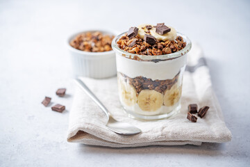 Chocolate and banana Greek yogurt granola parfait in a glass
