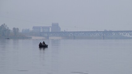 anglers catching fish from a boat on the Vistula River in Plock on a gray, foggy day 