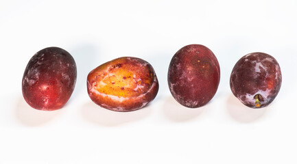 a row of four plums on a white background