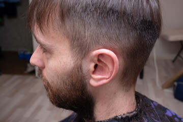 Obraz premium Barber makes a mens haircut in a barbershop. Process of creating hairstyles for men