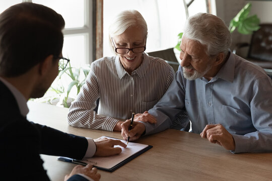 Place For Your Signature. Happy Husband Wife Pensioners Sit At Desk Sign Paper Document Invest Money Purchase Sell Realty Buy Life Medical Insurance Service At Financial Advisor Broker Insurer Office