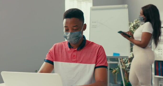 A busy woman stands at the blackboard holding a tablet, searches for the right graphic, prepares a diagram, a man sits at desk entering the data into the system needed to create the diagram