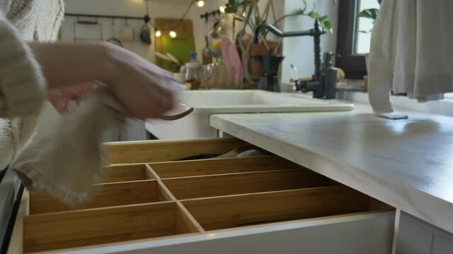 Woman take knife and fork form cupboard at kitchen