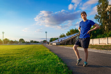 teen boy boy does physical exercises at the stadium track, a soccer field with green grass - concept of sports and health