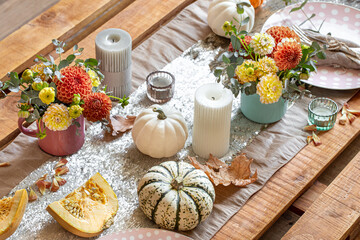 Festive table setting with pumpkins, candles and chrysanthemum flowers.