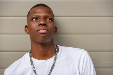 Afro young man looking up against a wall