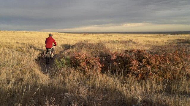 male cyclist is riding mountain bike on a single track trail in Colorado prairie - Soapstone Prairie Natural Area with last fall colors in late October