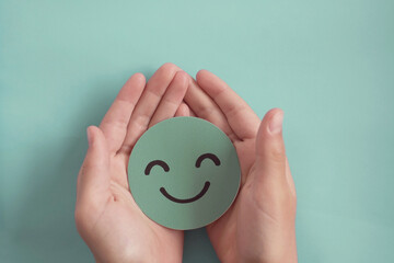 Hands holding green happy smile face, good feedback rating,positive customer review, experience,...