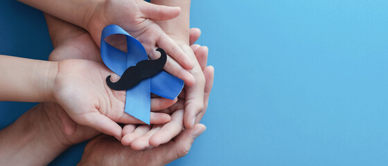Family hands holding light blue ribbonwith mustache on blue background , Prostate Cancer Awareness,...