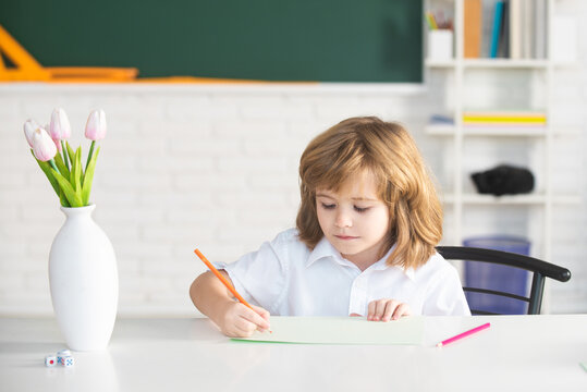 Pupil doing lessons at home. School kid writing something in copybook and sitting at table in classroom. First grader.