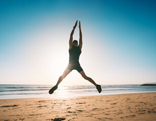 Fototapeta na wymiar Jumping man. Young fitness man doing jumping jacks or star jump exercise on the beach