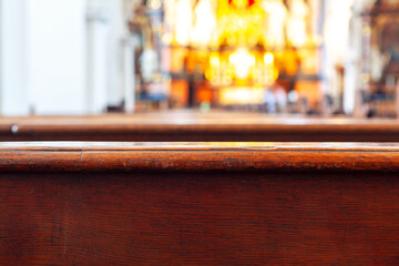 Wooden praying bench with blurry background . Inside of the church . Place for praying in cathedral