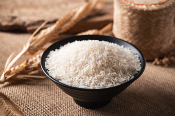 Organic Thai Jasmine rice grain in a black bowl on brown background