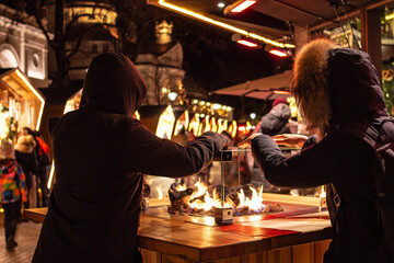 Kids holding their hands over fire place at traditional famous christmas market (christkindlmarkt)...