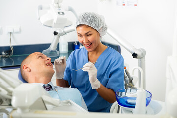 Obraz premium Young man patient who came to an appointment with a female dentist is sitting in a dental chair in the clinic office