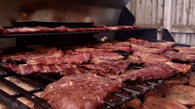 Home cooking - Close up of smoked and dehydrated beef jerky cooling in custom modified grill.