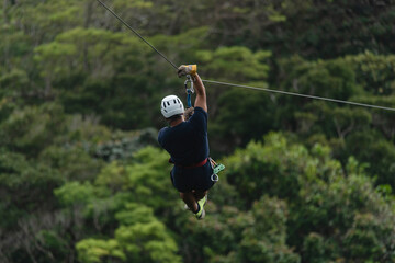 Hombre latino colgando de un cable ce canopi en la selva de Costa Rica