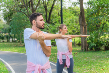 couple having stretching together before workout outdoors in park