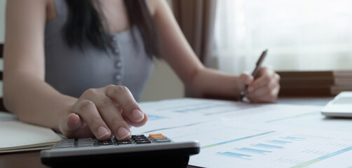 Close up woman using calculator and laptop for calaulating finance, tax, accounting, statistics and analytic research concept