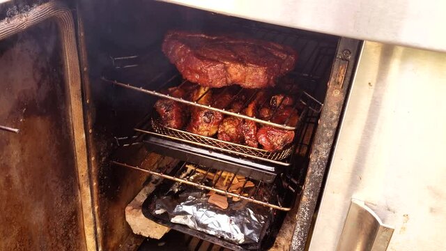 Home cooking - Pork riblets and beef cuck rye roast while being smoked in small gas smoker. Meat was previously marinated in barbeque rub.