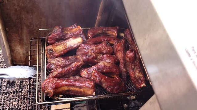 Home cooking - Checking pork riblets being smoked in small gas smoker. Meat was previously marinated in barbeque rub.