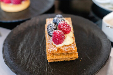 Tartlet with raspberries on the black plate on a serving table. High quality photo