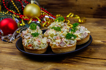 Traditional Russian festive salad Olivier in tartlets and Christmas decorations on wooden table