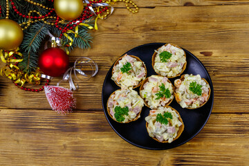 Traditional Russian festive salad Olivier in tartlets and Christmas decorations on wooden table. Top view