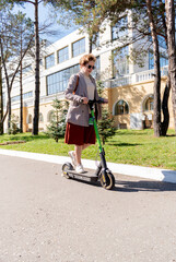 Middle aged adult woman riding an electric scooter around the city. Concept of using modern technology.