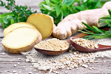 Ginger ground and flakes in spoons with root on board