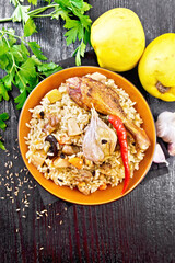 Pilaf with duck and quince in plate on black board top