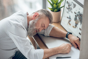 Obraz premium A man sleeping at the working place feeling tired