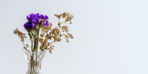 eine lila Blume mit weißen Trockenblumen in einer Glasvase dekoriert