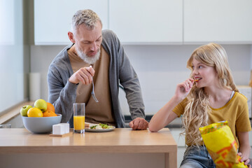 Dad trying to make his daughter eat breakfast