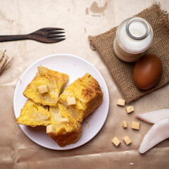 Coconut bread on white plate with a bottle of milk and an egg