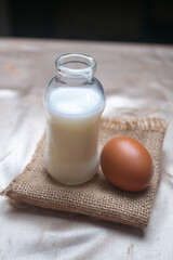A bottle of milk and an egg on gold cloth