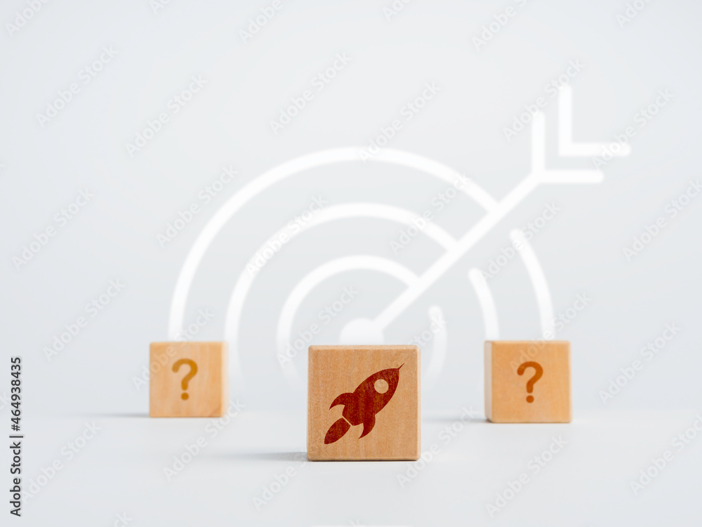 Poster business startup concept. wooden cube block with rocket symbol in front of two question mark sign wi