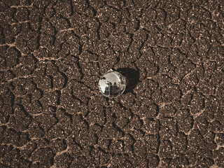 Glass globe on brown dried crack soil land background, top view. Crystal earth on crack floor background. Dryland. Global warming. Global heat effect.