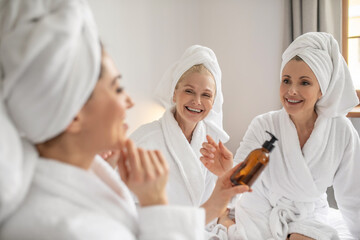 Obraz premium Three girlfriends with pleasure trying new cosmetic product