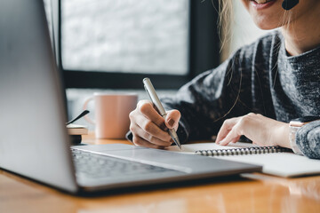 Close up photo of woman writing making list taking notes in notepad working or learning on laptop indoors- educational course or training, seminar, education online concept - obrazy, fototapety, plakaty