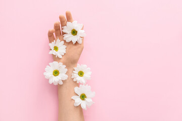 Female hand with flowers on color background