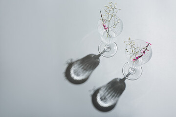 Beautiful empty glasses and flowers on grey background