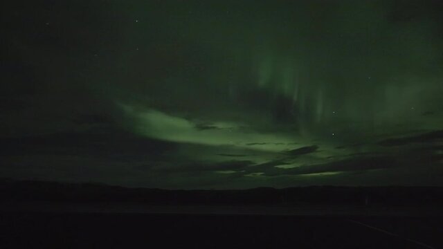 Northern Light Behind Clouds At Night. Natural Light Display In Earth's Sky. low angle, static