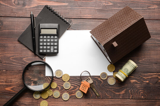 Blank paper with house model, money and stationery on dark wooden background