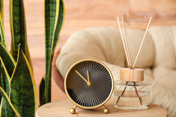 Alarm clock and aroma diffuser on table in stylish room