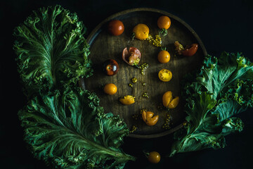 tomatoes and lettuce on the dining table. still life with bright yellow tomatoes and fresh salad on...
