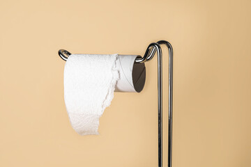Holder with cardboard tube for toilet paper on beige background, closeup