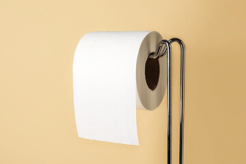 Holder with toilet paper roll on beige background, closeup