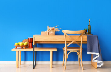 Wooden chair and tables with decor near color wall