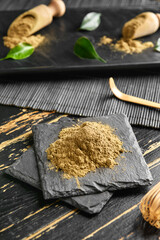 Pile of hojicha powder on black wooden background